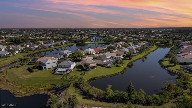 aerial view at dusk featuring a water view