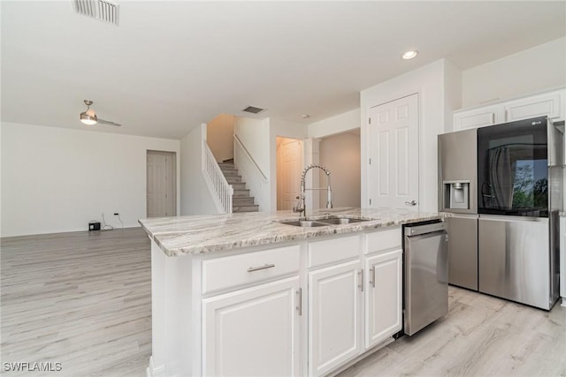 kitchen featuring sink, light hardwood / wood-style flooring, a kitchen island with sink, white cabinets, and appliances with stainless steel finishes