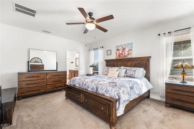 bedroom featuring light carpet, connected bathroom, and ceiling fan