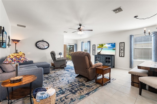 tiled living room with ceiling fan with notable chandelier