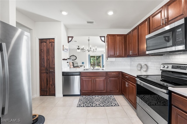 kitchen with decorative backsplash, appliances with stainless steel finishes, sink, pendant lighting, and an inviting chandelier