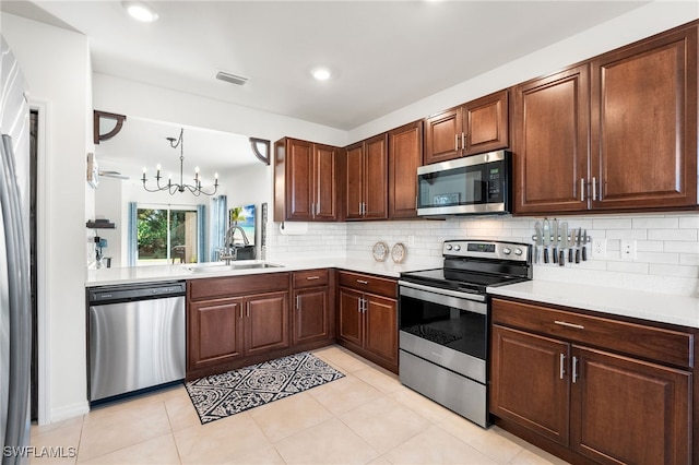 kitchen with backsplash, sink, decorative light fixtures, appliances with stainless steel finishes, and a notable chandelier