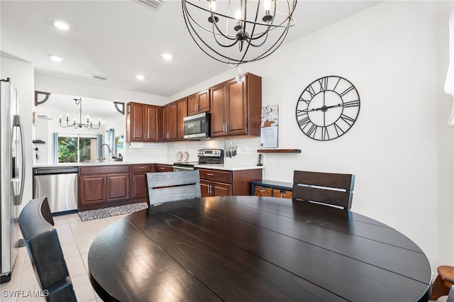 dining space with sink, light tile patterned floors, and a chandelier