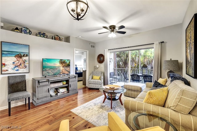 living room featuring baseboards, visible vents, wood finished floors, and ceiling fan with notable chandelier