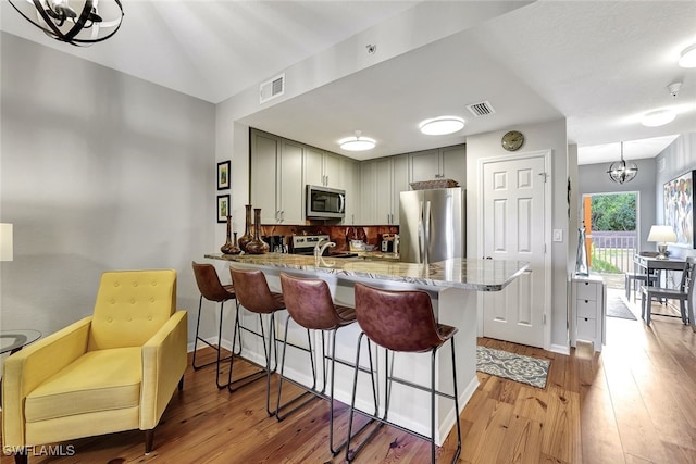 kitchen featuring a peninsula, gray cabinets, visible vents, and stainless steel appliances