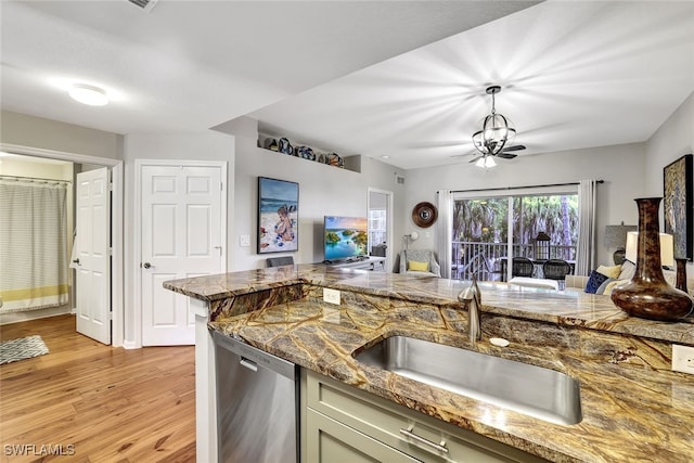 kitchen with light wood finished floors, green cabinetry, dishwasher, pendant lighting, and a sink