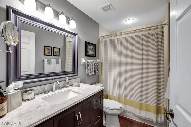 bathroom featuring toilet, curtained shower, visible vents, and vanity