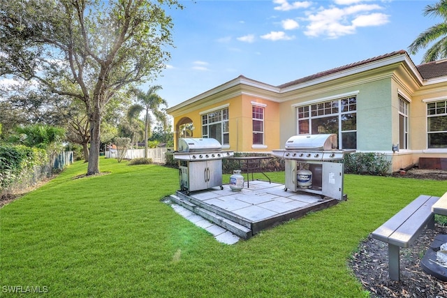 back of property featuring a yard, fence, and stucco siding