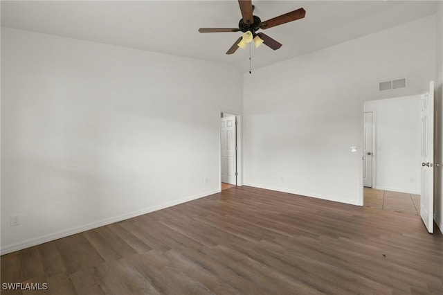 spare room with dark hardwood / wood-style floors, ceiling fan, and a towering ceiling