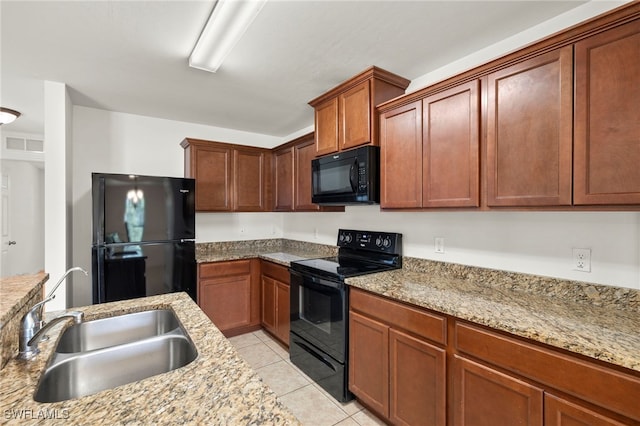 kitchen featuring black appliances, light stone countertops, light tile patterned floors, and sink