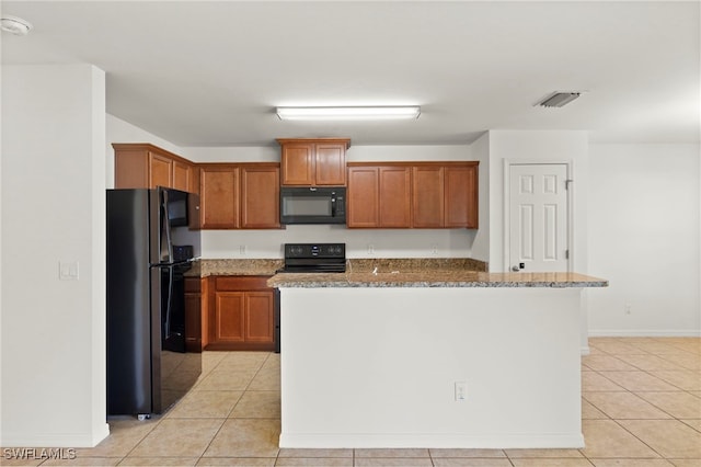 kitchen featuring dark stone counters, an island with sink, black appliances, and light tile patterned floors