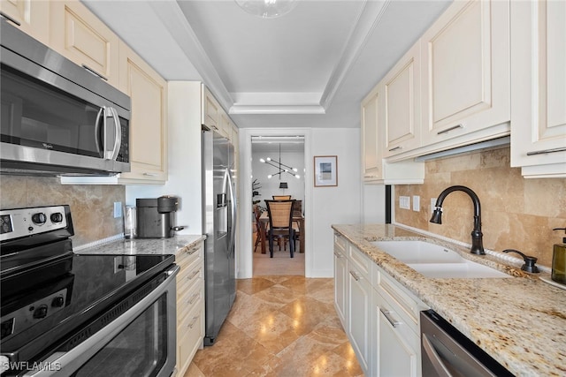 kitchen with an inviting chandelier, sink, appliances with stainless steel finishes, tasteful backsplash, and light stone counters