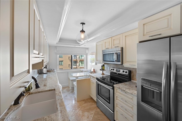 kitchen with cream cabinetry, sink, stainless steel appliances, and hanging light fixtures