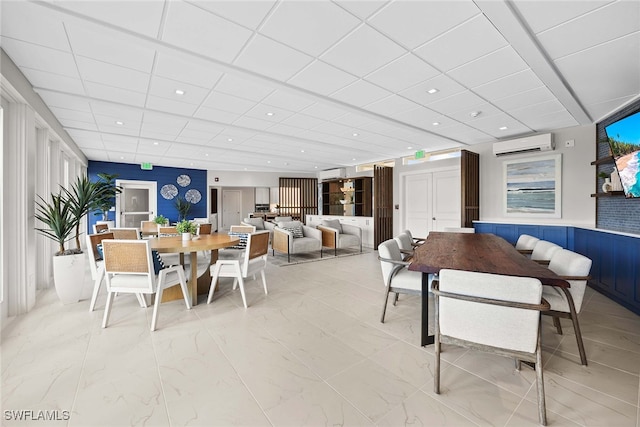 dining room with a paneled ceiling and a wall unit AC