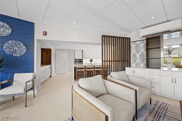 living room with a wall mounted air conditioner and a paneled ceiling