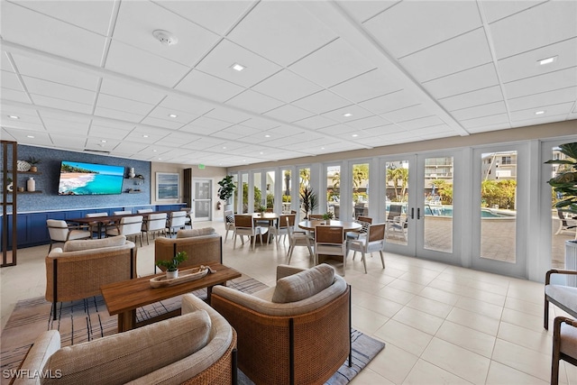 living room featuring french doors, a paneled ceiling, and light tile patterned floors