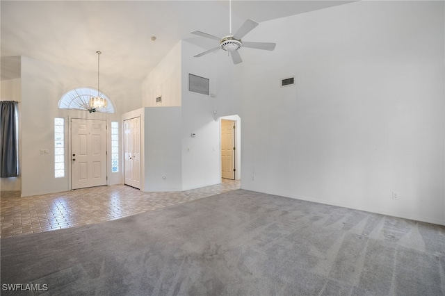 carpeted entryway featuring ceiling fan with notable chandelier and high vaulted ceiling