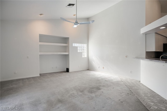 unfurnished living room with light carpet, high vaulted ceiling, and ceiling fan