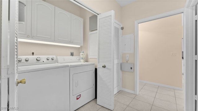 clothes washing area with washer and dryer, light tile patterned floors, and cabinets