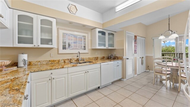 kitchen with dishwasher, white cabinets, light stone counters, and sink