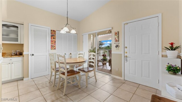 tiled dining room featuring a notable chandelier and lofted ceiling