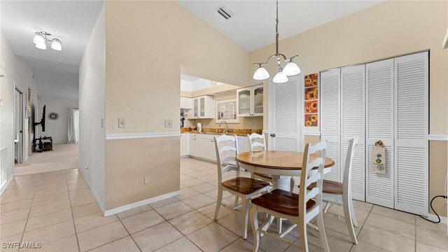 tiled dining room featuring lofted ceiling and a notable chandelier