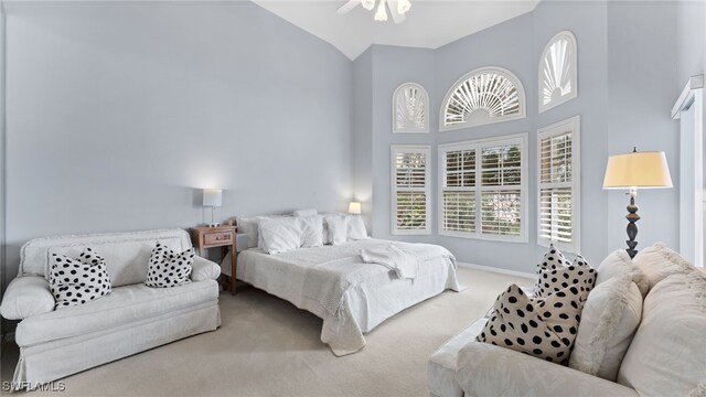 bedroom with ceiling fan, light colored carpet, and vaulted ceiling