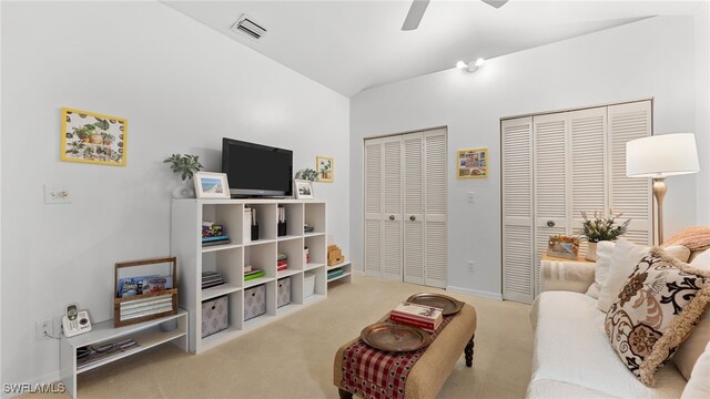 carpeted living room with ceiling fan and vaulted ceiling