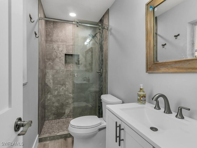 bathroom with hardwood / wood-style floors, vanity, toilet, and an enclosed shower