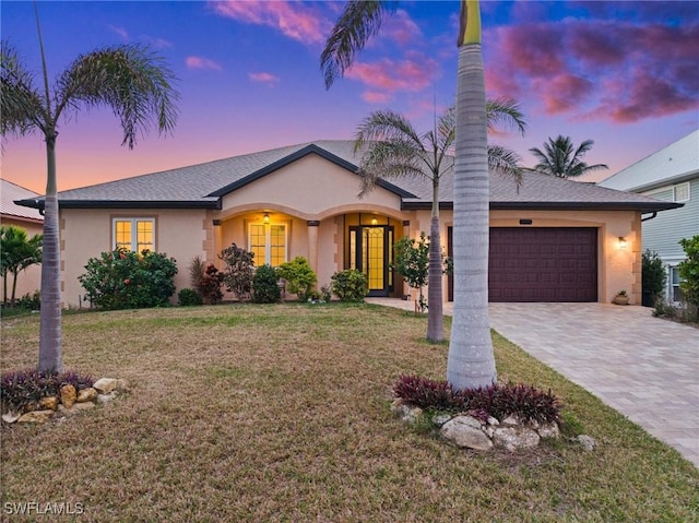 ranch-style home featuring a lawn and a garage