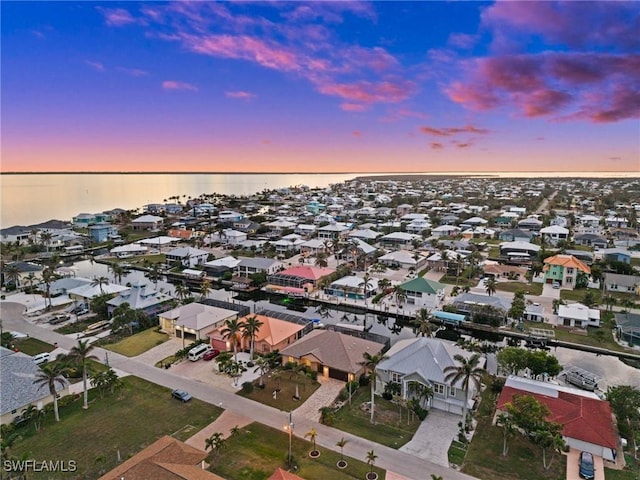 aerial view at dusk featuring a water view