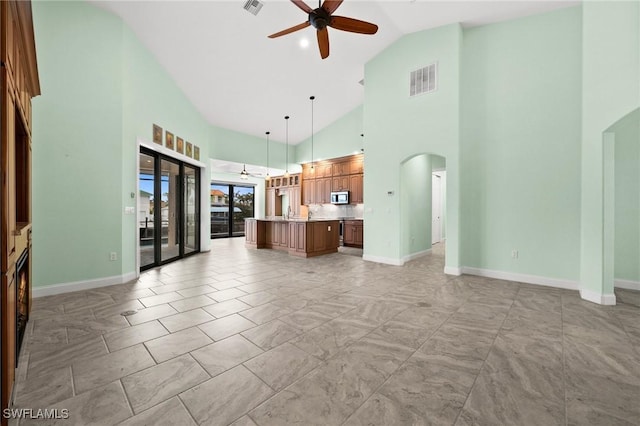 unfurnished living room with high vaulted ceiling and ceiling fan