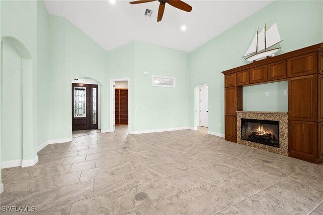 2405 Cherimoya Ln, Saint James City, FL 33956 - unfurnished living room featuring a ceiling fan, high vaulted ceiling, arched walkways, and a glass covered fireplace