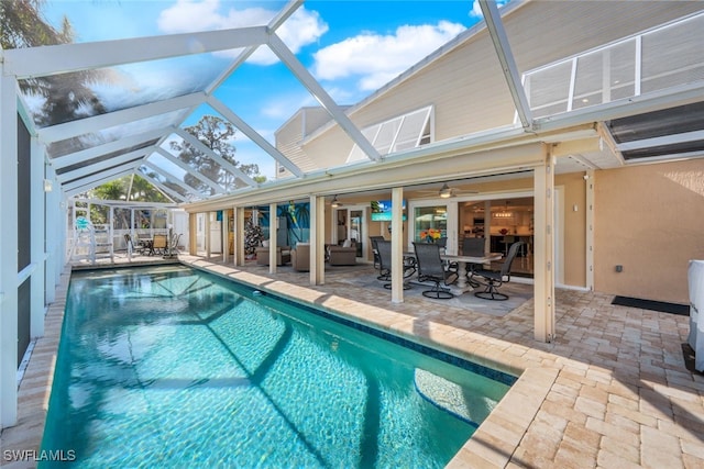 view of pool with an outdoor living space, ceiling fan, a lanai, and a patio