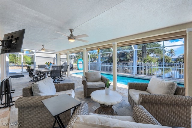 sunroom / solarium with ceiling fan and a water view