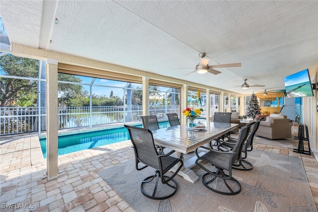 sunroom / solarium featuring ceiling fan and a water view