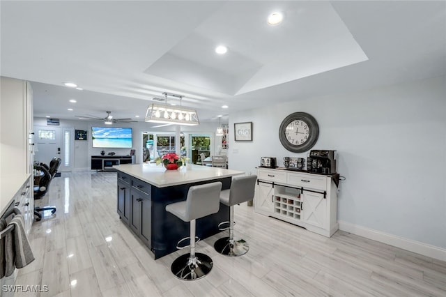 kitchen with ceiling fan, white cabinetry, decorative light fixtures, a kitchen bar, and a kitchen island