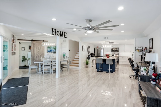 living room featuring ceiling fan and a barn door