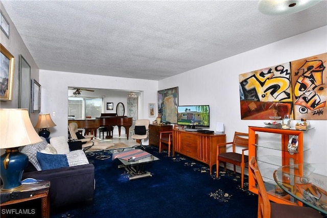 living room featuring ceiling fan and a textured ceiling