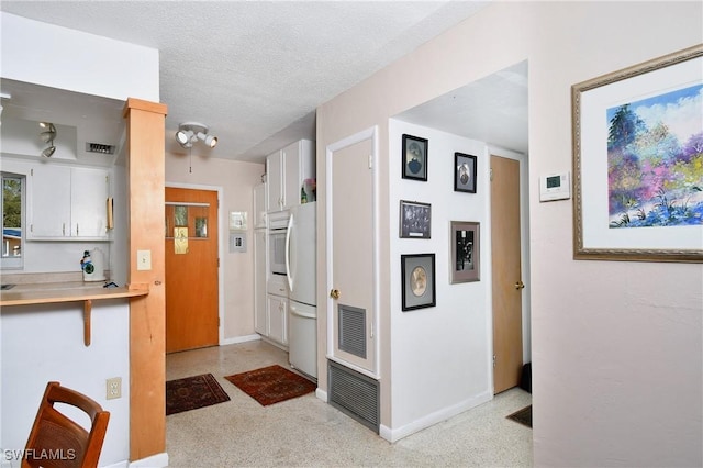 kitchen featuring white cabinetry, white fridge, and a textured ceiling