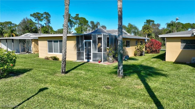 rear view of property featuring a lawn and a sunroom