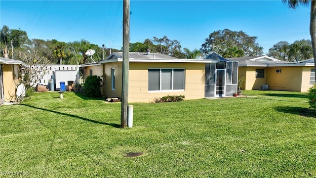 rear view of property featuring a sunroom and a yard