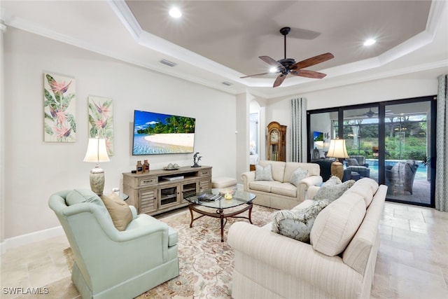 living room with a tray ceiling, ceiling fan, and crown molding