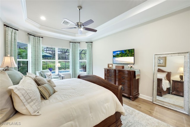 bedroom featuring ceiling fan, light wood-type flooring, crown molding, and a tray ceiling