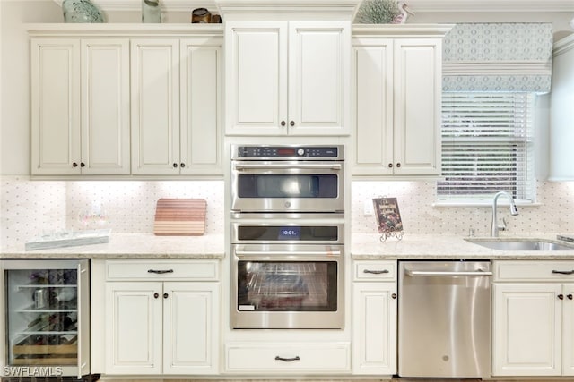 kitchen with light stone countertops, appliances with stainless steel finishes, backsplash, sink, and wine cooler