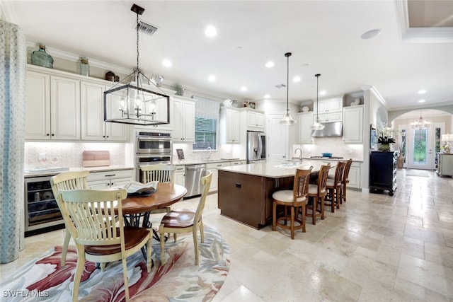 kitchen featuring a kitchen breakfast bar, backsplash, stainless steel appliances, pendant lighting, and a center island with sink