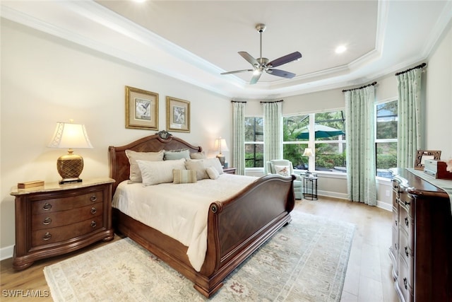 bedroom featuring ceiling fan, light hardwood / wood-style floors, a raised ceiling, and crown molding