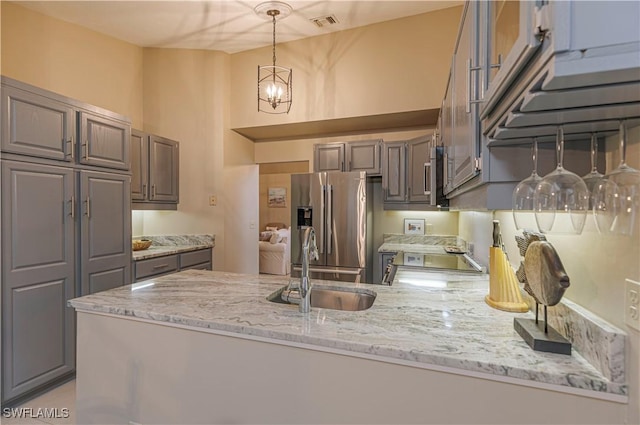 27062 Kindlewood Ln, Bonita Springs, FL 34134 - kitchen with stainless steel appliances, gray cabinetry, a chandelier, light stone counters, and decorative light fixtures