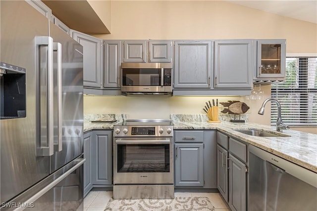 27062 Kindlewood Ln, Bonita Springs, FL 34134 - kitchen with appliances with stainless steel finishes, gray cabinets, light tile patterned flooring, lofted ceiling, and light stone countertops