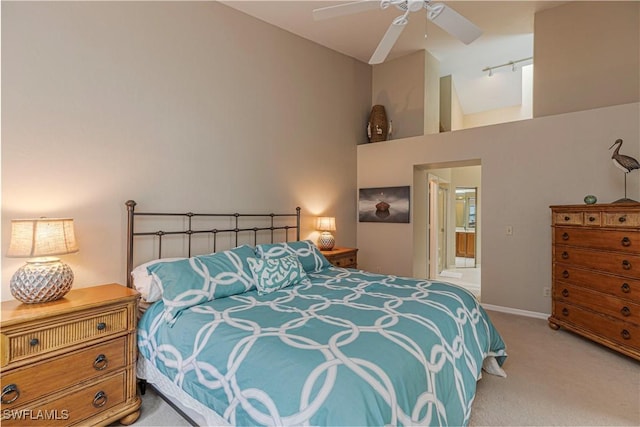 carpeted bedroom with ensuite bath, ceiling fan, and high vaulted ceiling